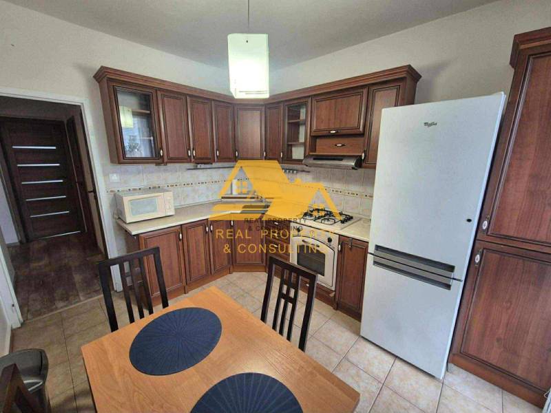 Küche mit dunklem Holzdekor, Herd und Kühlschrank in einer 3-Zimmer-Wohnung.