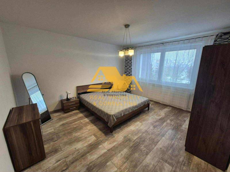 Schlafzimmer in einer 3-Zimmer-Wohnung mit Bett, Spiegel und Boden mit Holzdekor.
