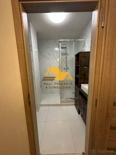 Badezimmer mit Dusche und Waschbecken in einer 2-Zimmer-Wohnung, mit Fliesen in hellen Tönen.