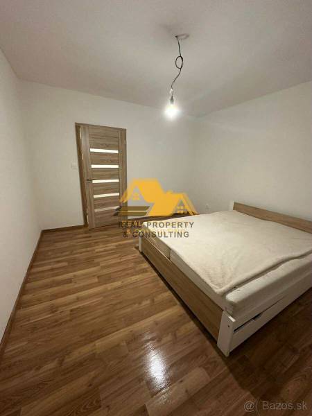 Schlafzimmer in einer 2-Zimmer-Wohnung mit Bett, Holzboden-Dekor und einfacher Beleuchtung.