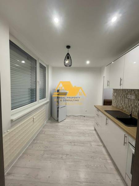 Küche in einer Einzimmerwohnung mit Holzboden und moderner Beleuchtung.