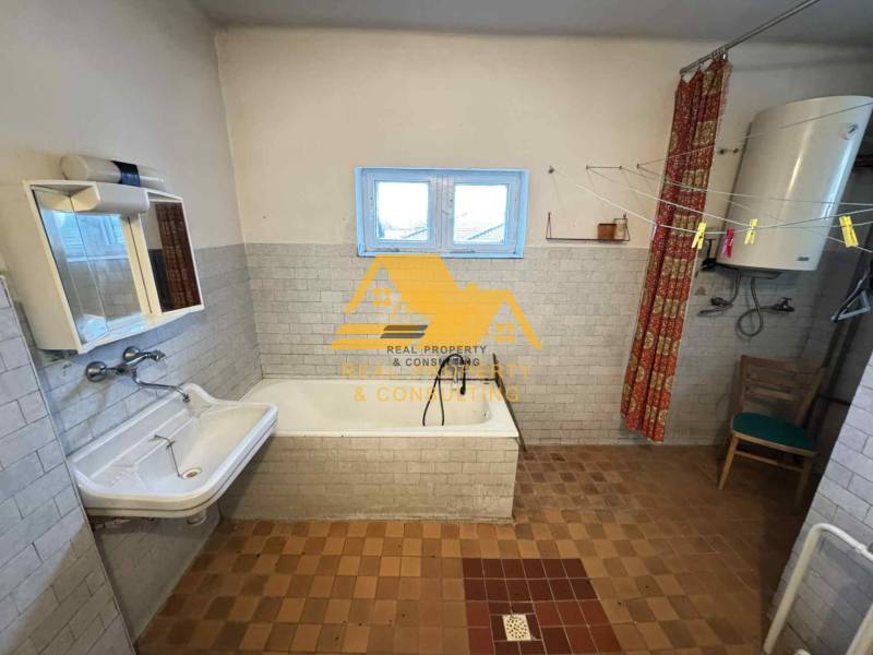Badezimmer in einem Einfamilienhaus mit Badewanne, Waschbecken und Boiler.
