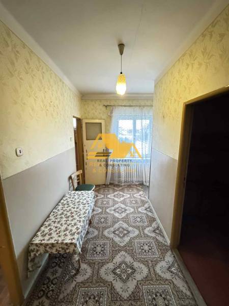 Ein Flur in einem Einfamilienhaus mit Teppichdekor und einem Tisch, Fenster am Ende des Raumes.