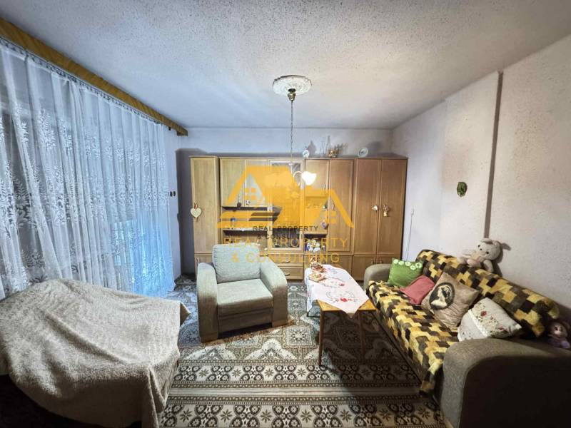 Wohnzimmer in einem Einfamilienhaus mit Sofa, Teppich und Schränken mit Dekorationen.