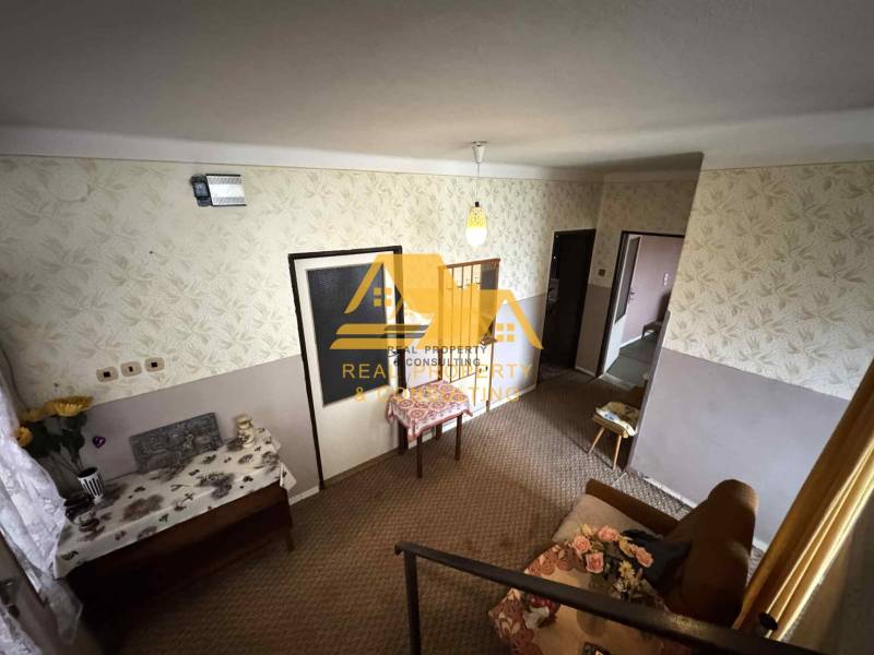 Innenraum eines Einfamilienhauses mit gemusterten Tapeten, Möbeln und Blumendekoration.