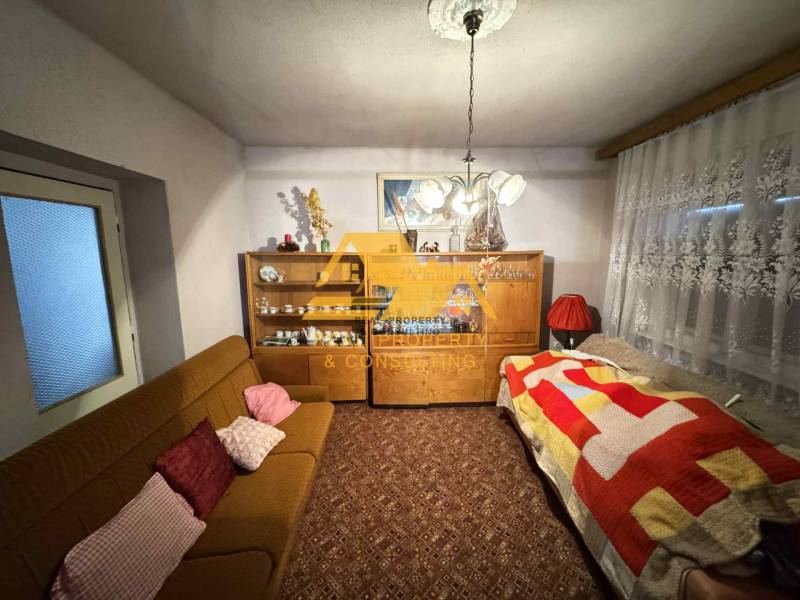 Wohnzimmer in einem Einfamilienhaus mit Teppich, Sofa und Schrank mit Porzellan.