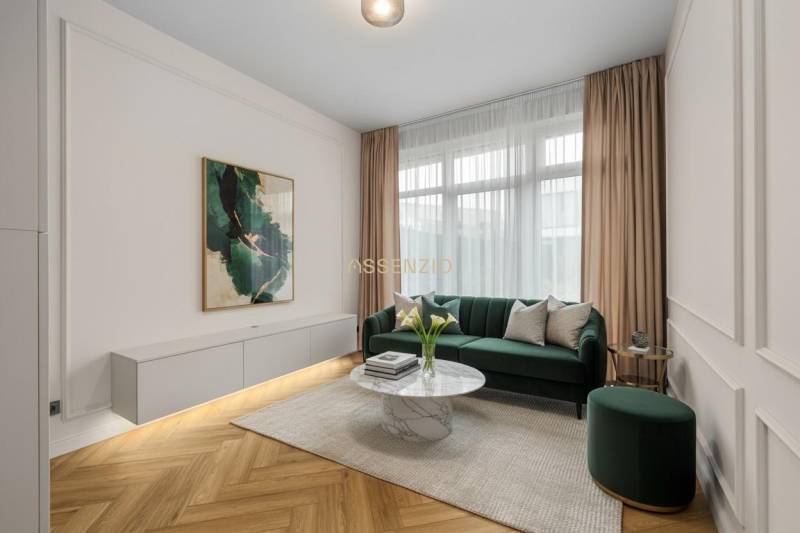 Wohnzimmer mit einem grünen Sofa, einem dekorativen Tisch und einem Boden in Holzoptik.