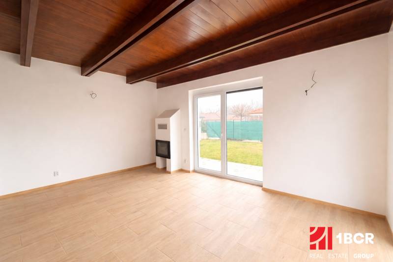 Innenraum eines Einfamilienhauses mit Holzboden und großen Fenstern zum Garten.