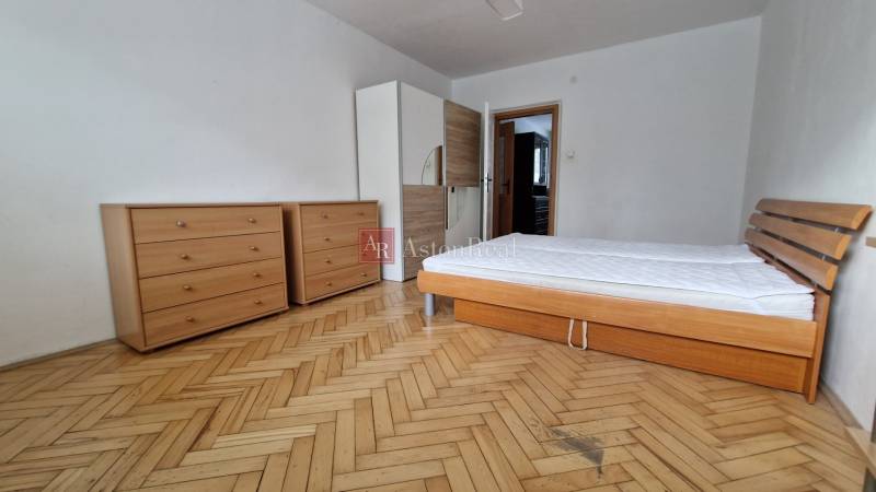 Schlafzimmer in einer 2-Zimmer-Wohnung mit Bett, Kommoden und Holzboden.