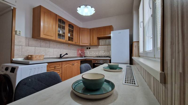 Küche mit Holzschränken und Esstisch in einer 2-Zimmer-Wohnung.