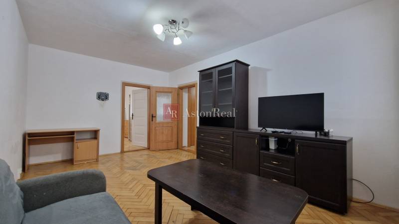 Wohnzimmer mit dunklen Möbeln und Holzboden in einer Zweizimmerwohnung.