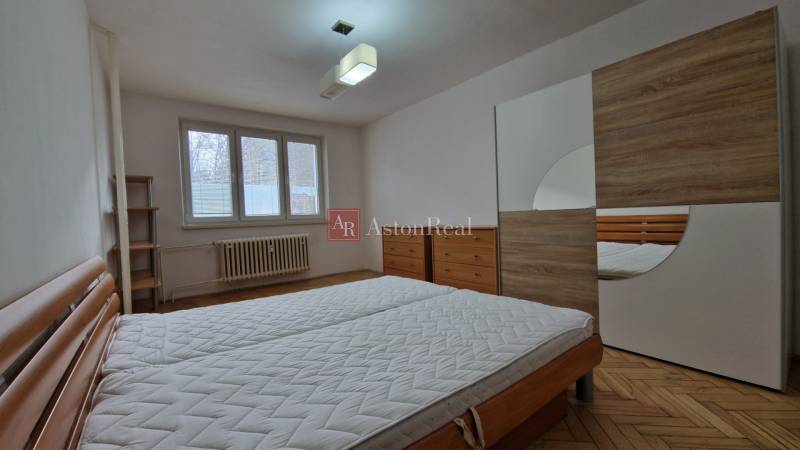 Schlafzimmer mit Bett, Einbauschrank und Boden mit Holzdekor in einer 2-Zimmer-Wohnung.