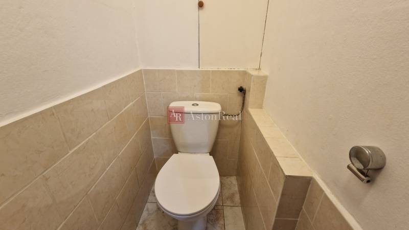 Toilette mit Fliesen in einer 2-Zimmer-Wohnung mit einfacher Ausstattung.