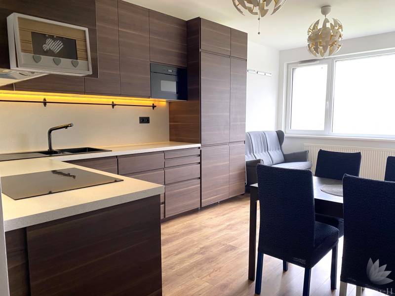 Küche in einer 3-Zimmer-Wohnung mit dunklen Möbeln und einem Boden in Holzoptik.