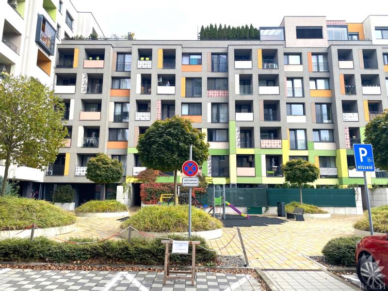 Bunte Wohnhäuser in der Nejedlého-Straße in Bratislava - Dúbravka, mit einem Parkplatz.