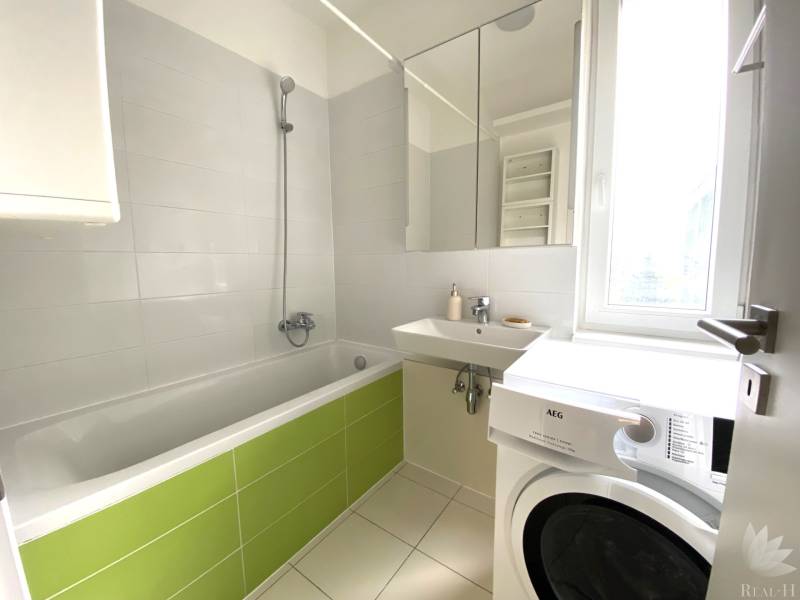 Badezimmer mit Dusche, Badewanne, Waschbecken und Waschmaschine in einer 3-Zimmer-Wohnung.
