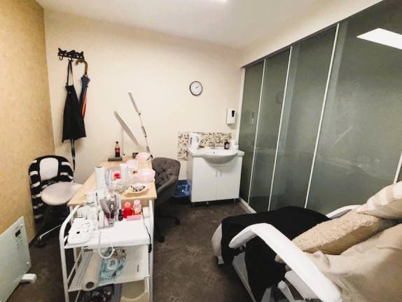 Kosmetiksalon mit Stuhl, Tisch und Waschbecken in Geschäftsräumen.