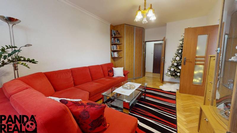 Wohnzimmer in einer 3-Zimmer-Wohnung mit rotem Sofa, Tannenbaum und Holzboden.