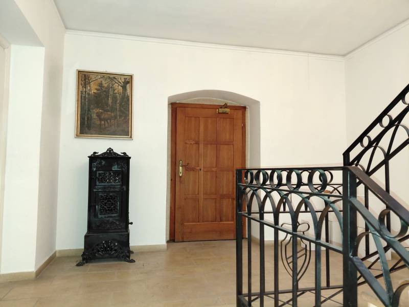 Flur im Büro mit Gemälde, Holztüren und Kachelofen.