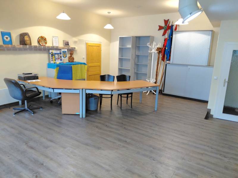 Büros mit Holzboden, Tischen und Stühlen, dekoriert mit Flaggen und Gegenständen.