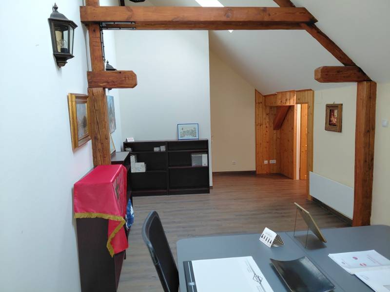 Büros mit Balken und Holzboden, Regale mit Decke, Tisch mit Dokumenten.