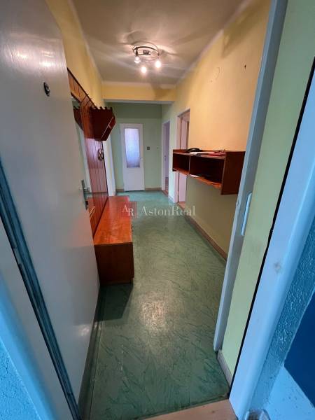 Der Flur in der 3-Zimmer-Wohnung mit Einbaumöbeln und grünem Boden.