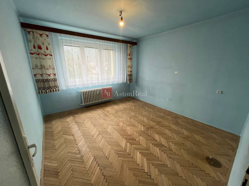 Blaues Zimmer mit großem Fenster und Holzboden in einer 3-Zimmer-Wohnung.