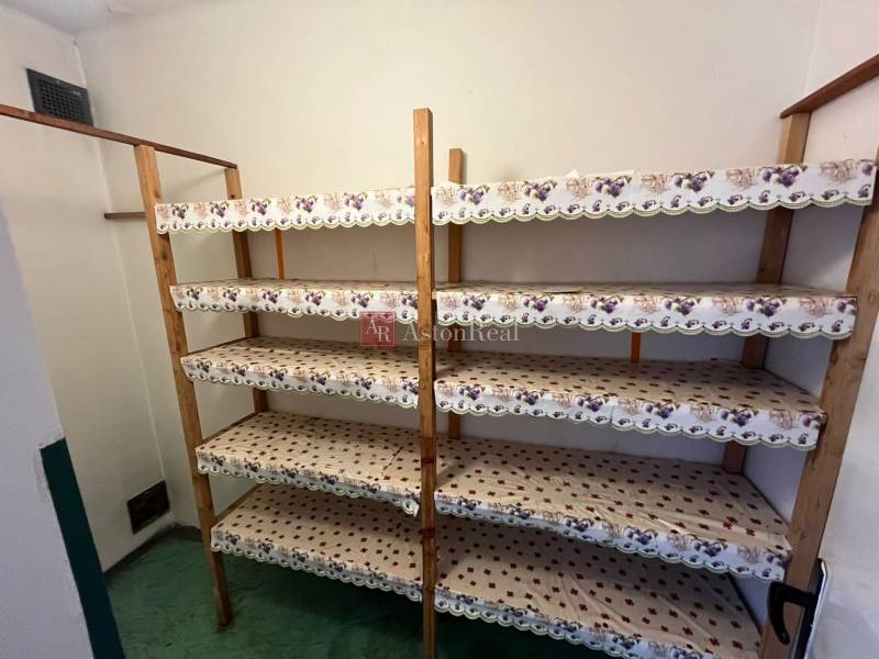 Stauraum in einer 3-Zimmer-Wohnung mit Holzregalen und grünem Boden.