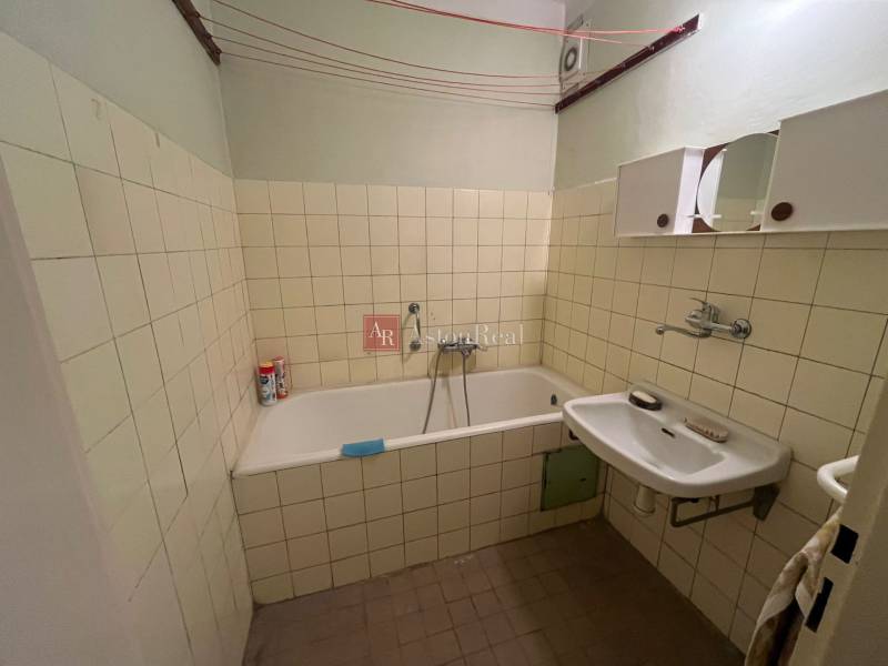 Badezimmer in einer 3-Zimmer-Wohnung mit Badewanne, Waschbecken und Fliesen an den Wänden.