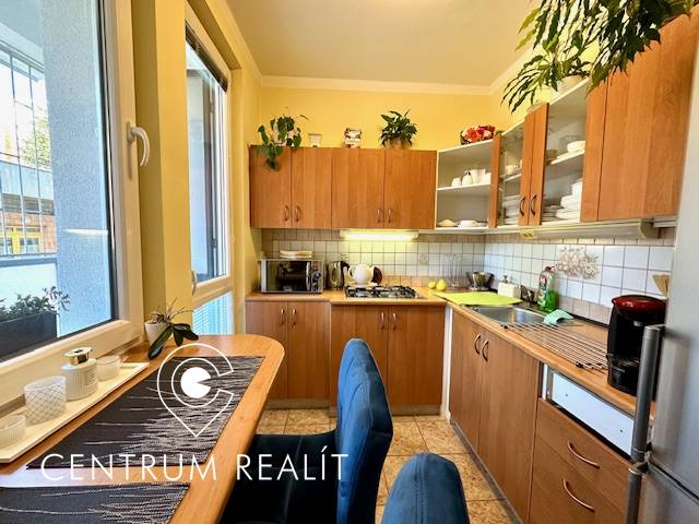 Küche in einer Einzimmerwohnung mit Holzschränken und Esstisch.