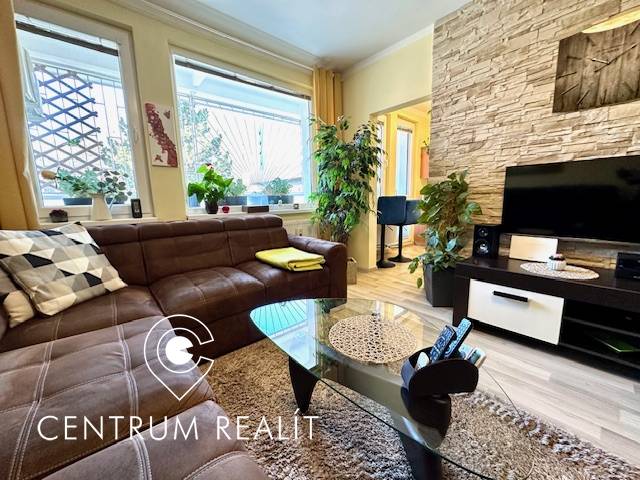 Wohnzimmer in einer Einzimmerwohnung mit braunem Sofa und Boden in Holzoptik.