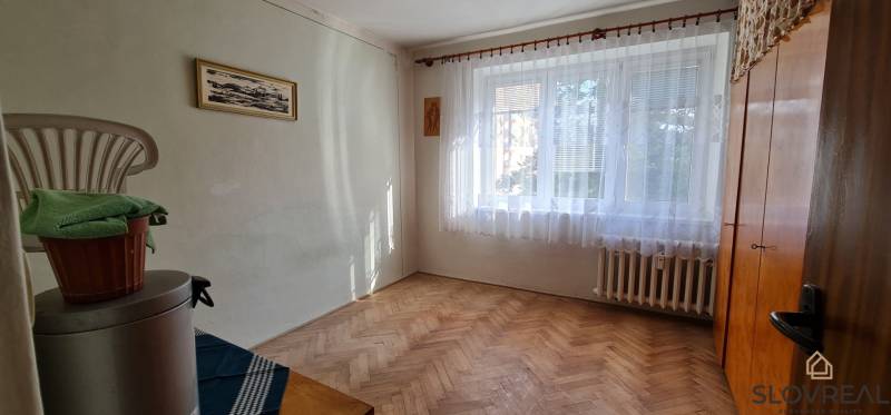 Ein Zimmer mit einem Fenster und einem Boden in Holzoptik in einer 3-Zimmer-Wohnung.