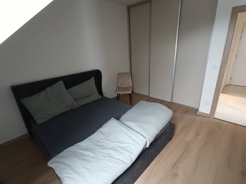 Schlafzimmer in einer 2-Zimmer-Wohnung mit Bett und Kleiderschrank, Boden mit Holzdekor.