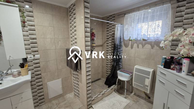 Ein Badezimmer in einem Einfamilienhaus mit Fliesen und einer Dusche, dekoriert mit Blumen.