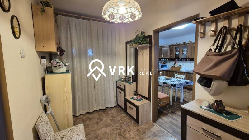 Eingangsbereich in einem Einfamilienhaus mit Garderobe, Spiegel und Zugang zur Küche mit Esstisch.