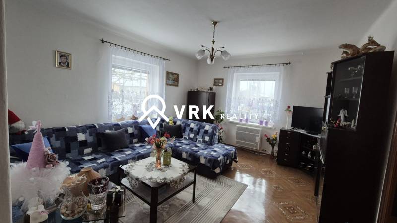 Ein Einfamilienhaus mit einem Sofa, einem Schrank, einem Fernseher, Dekorationen und einem Boden mit Holzdekor.