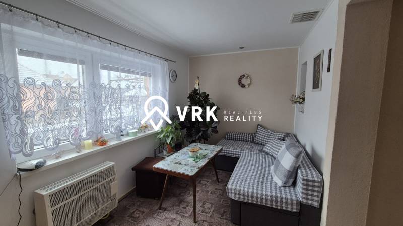 Wohnzimmer in einem Einfamilienhaus mit Sofa, Tisch und Fenster mit Vorhang.