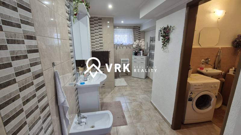 Ein Badezimmer in einem Einfamilienhaus mit einer gefliesten Wand, einem Bidet, einer Waschmaschine und Dekorationen.