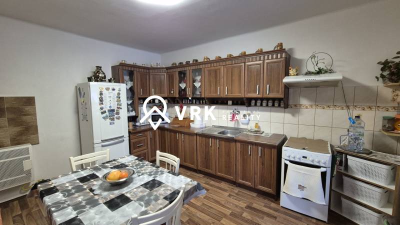 Küche in einem Einfamilienhaus mit Küchenzeile, Esstisch und Boden in Holzoptik.