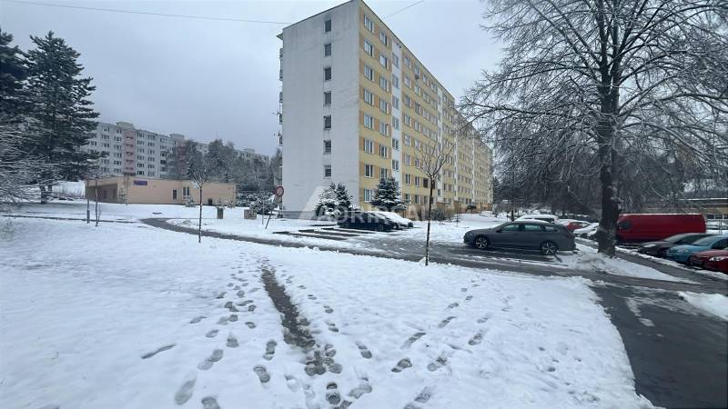 Winterszene in der Bazovského-Straße in Zvolen mit einem Plattenbau und geparkten Autos.