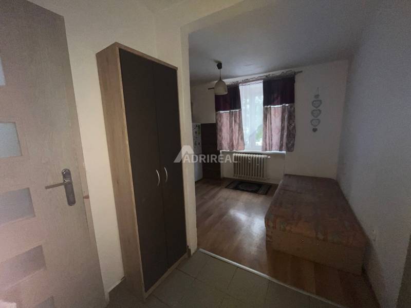 In der Einzimmerwohnung sieht man einen Boden mit Holzdekor, ein Bett und einen Schrank.