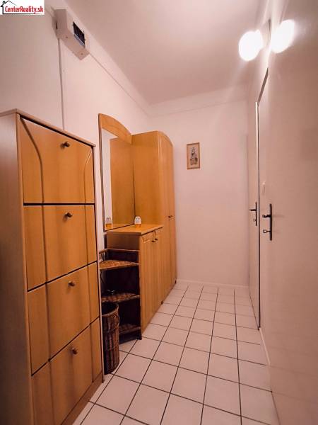 Der Flur in einer 2-Zimmer-Wohnung mit Fliesenboden und Holzmöbeln.