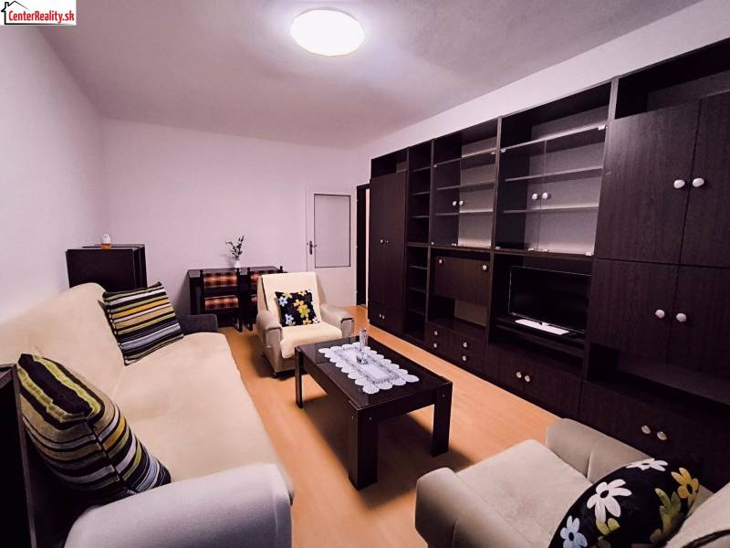 Wohnzimmer mit Sofa, Sessel, dunklen Möbeln und Boden mit Holzdekor in einer 2-Zimmer-Wohnung.