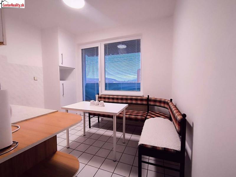 Küche mit Eckbank, Tisch und Fenster in einer 2-Zimmer-Wohnung.