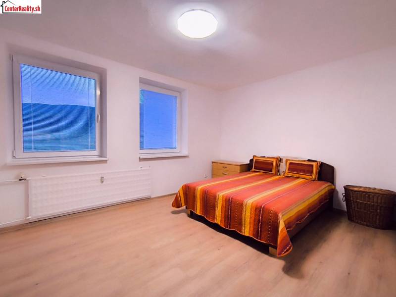 Schlafzimmer in einer 2-Zimmer-Wohnung mit Doppelbett, Holzboden und einfacher Einrichtung.