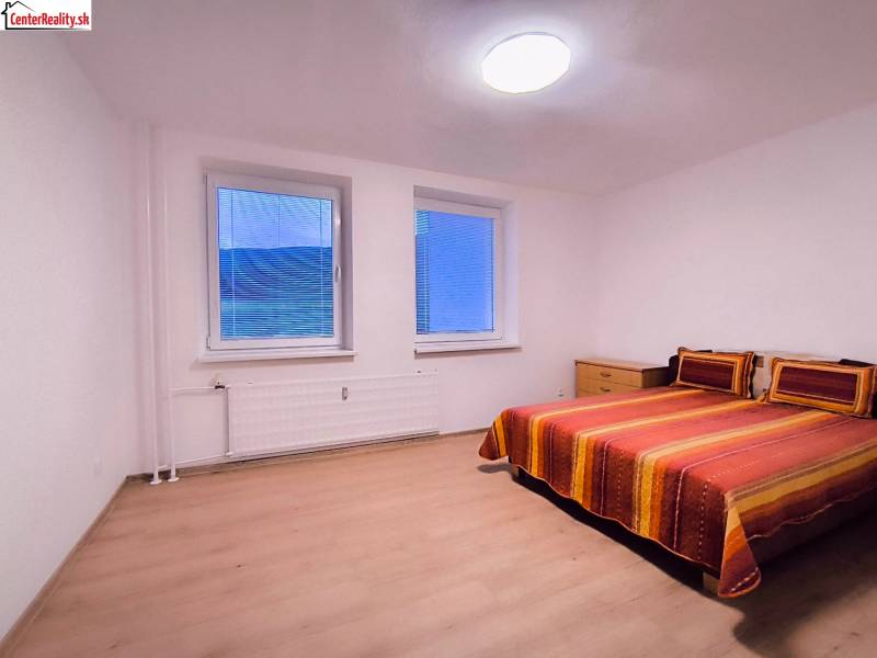 Schlafzimmer mit einem farbigen Bett und einem Holzboden in einer 2-Zimmer-Wohnung.