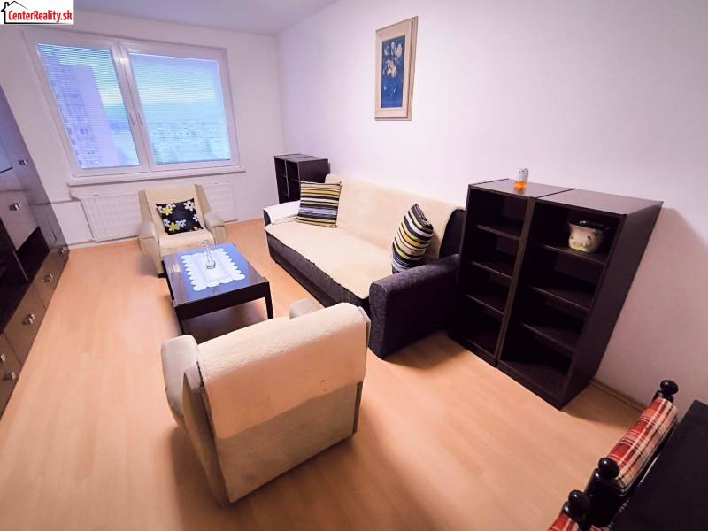 Wohnzimmer in einer 2-Zimmer-Wohnung mit bequemen Sitzgelegenheiten und einem Boden in Holzoptik.