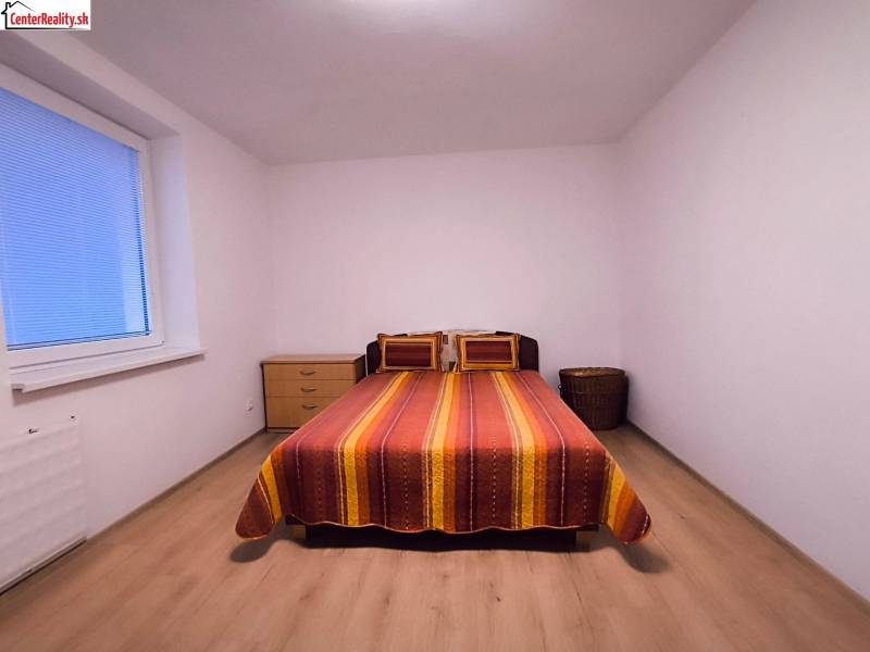 Schlafzimmer in einer 2-Zimmer-Wohnung mit Bett, Nachttisch und Boden in Holzoptik.