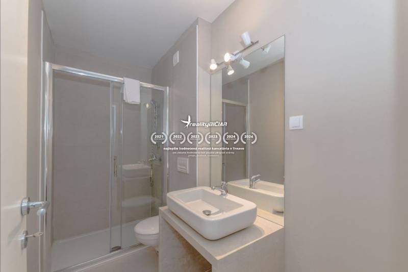 Badezimmer in einer Ferienwohnung mit Waschbecken, Duschkabine und großem Spiegel.