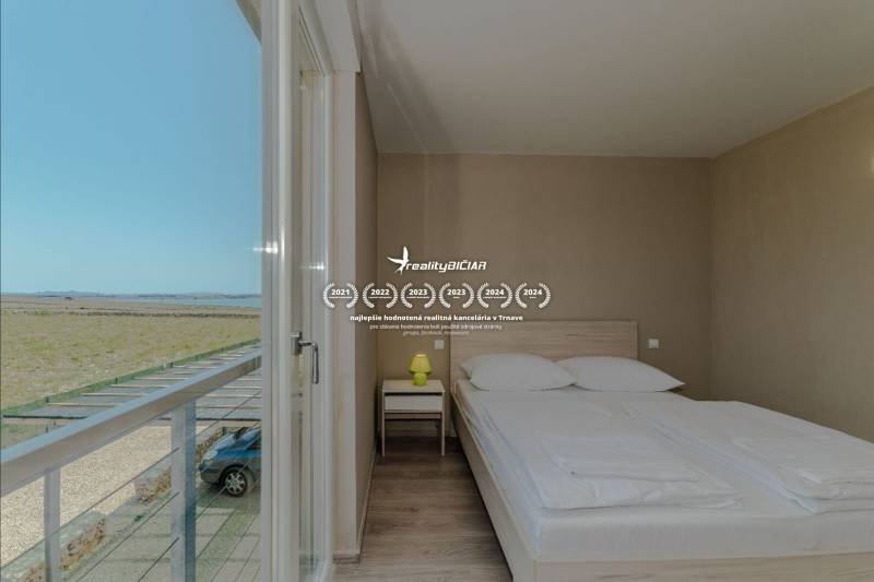 Schlafzimmer im Ferienapartment mit Aussicht, Bett und Boden in Holzoptik.